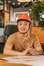 Smiling professional with hard hat seated indoors, symbolizing safety and construction management.